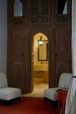 a bathroom with a tub and a mirror and two chairs at Riad Tzarra in Marrakech