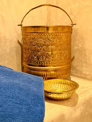 a golden bucket with writing on it next to a bowl at Riad Tzarra in Marrakech