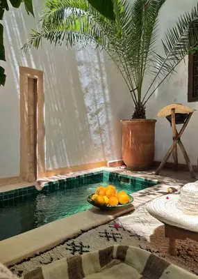 a bowl of oranges on a table next to a swimming pool at Riad Dar Zaman in Marrakech