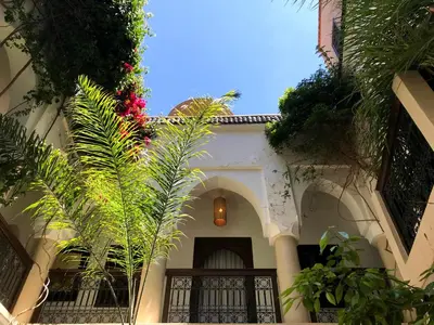 a white building with a gate and some plants at Riad Dar Zaman in Marrakech