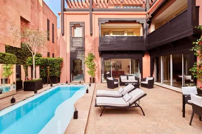 an apartment patio with a swimming pool and lounge chairs at Hôtel & Ryads Barrière Le Naoura in Marrakech