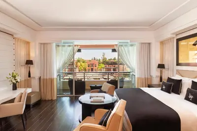 a hotel room with a large bed and a balcony at Hôtel & Ryads Barrière Le Naoura in Marrakech