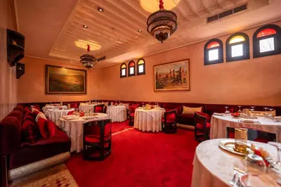 a restaurant with white tables and red carpet at Al Fassia Aguedal in Marrakech