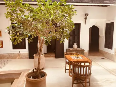 a table and chairs and a tree in a courtyard at Riad Les 5 Soeurs in Marrakech