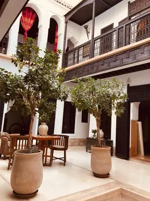 a courtyard with trees and a table and chairs at Riad Les 5 Soeurs in Marrakech