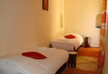 a room with two beds with red towels on them at Riad Al Faras in Marrakech