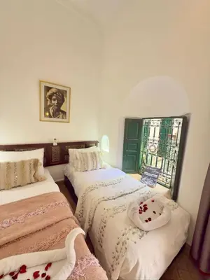 a bedroom with two beds and a window at Riad Al Karama in Marrakech