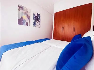 a small bedroom with a bed with blue pillows at Ehden Properties - Appt luxueux dans la residence golfique Prestigia Argan in Marrakech