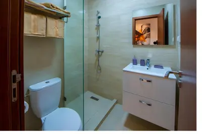 a bathroom with a toilet and a glass shower at Ehden Properties - Appt luxueux dans la residence golfique Prestigia Argan in Marrakech