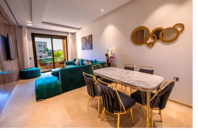 a living room with a table and a green couch at Ehden Properties - Appt luxueux dans la residence golfique Prestigia Argan in Marrakech