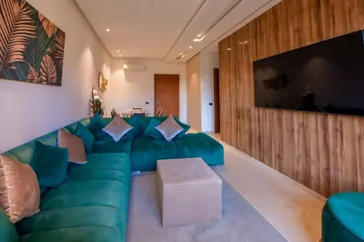 a living room with a green couch and a flat screen tv at Ehden Properties - Appt luxueux dans la residence golfique Prestigia Argan in Marrakech