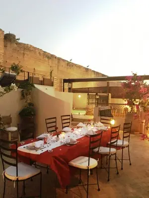 a long table with a red table cloth and chairs at Riad Carina in Marrakech