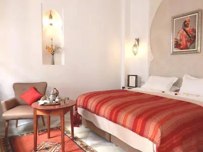a bedroom with a bed and a chair and a table at Riad Carina in Marrakech