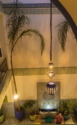 a chandelier hanging in a room with a palm tree at Riad Med Agorà in Marrakech