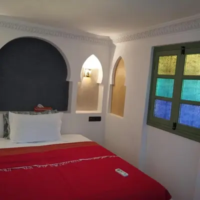 a bedroom with a bed with a red blanket and a window at Riad Med Agorà in Marrakech