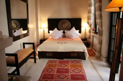 a bedroom with a bed and a chair and lamps at Riad Diana in Marrakech