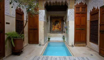 a swimming pool in a building with wooden doors at Riad Dar Zaya in Marrakech
