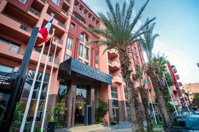 a hotel with palm trees in front of a building at Imperial Holiday Hôtel & spa in Marrakech