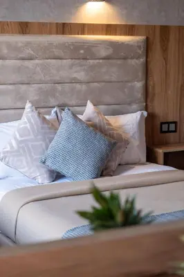a bed with white pillows and a wooden headboard at Imperial Holiday Hôtel & spa in Marrakech