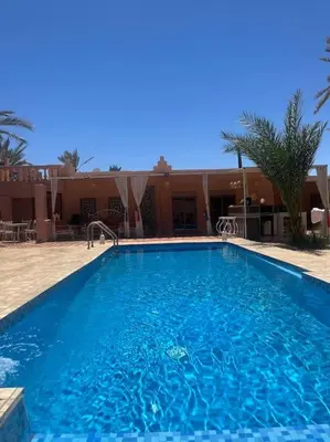 a large blue swimming pool in front of a house at Villa Oasis de la Palmeraie in Marrakech