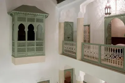 a white wall with green doors and a balcony at Riad Les Hibiscus in Marrakech