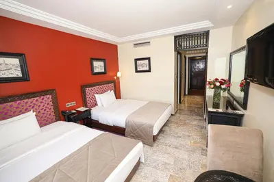 a hotel room with two beds and red walls at El Andalous Lounge & Spa Hotel in Marrakech