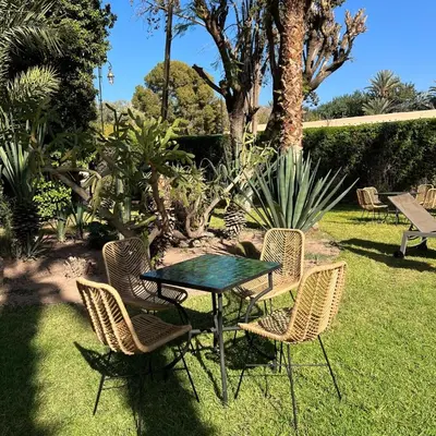 a table and chairs in a yard with a palm tree at The Red House in Marrakech