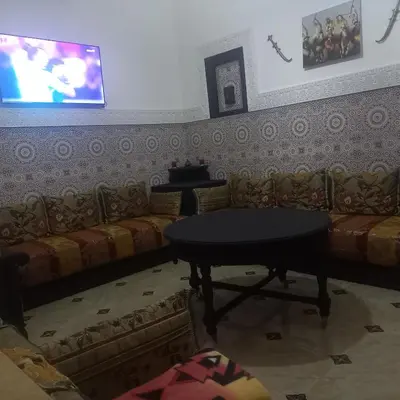 a room with a couch and a table and a tv at Riad Al Nakhil in Marrakech
