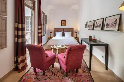 a bedroom with a bed and two chairs and a table at Riad Altair in Marrakech