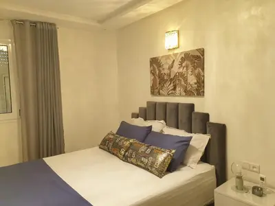 a bedroom with a bed and a painting on the wall at Bel appartement moderne au cœur de guelize in Marrakech