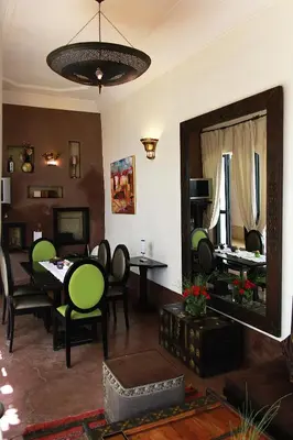 a living room with a table and chairs and a mirror at Riad Davia in Marrakech