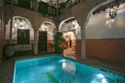 a large swimming pool in a building with a pool at Riad Itrane in Marrakech