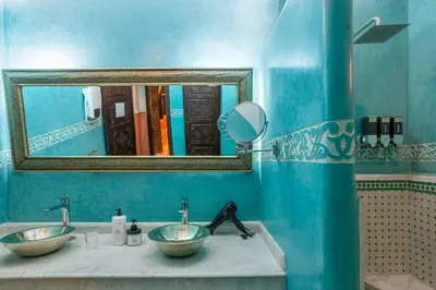 a blue bathroom with two sinks and a mirror at Riad Itrane in Marrakech