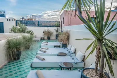 a row of beds on a patio with a palm tree at Riad Spa Sindibad in Marrakech
