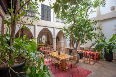 a patio with tables and chairs and trees at Riad Spa Sindibad in Marrakech