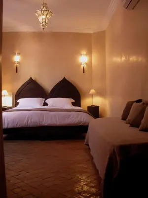 a bedroom with two beds and a chandelier at Riad Aderbaz in Marrakech