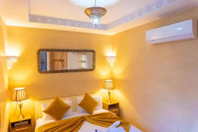 a bedroom with two beds and a mirror and lamps at Riad Louaya in Marrakech