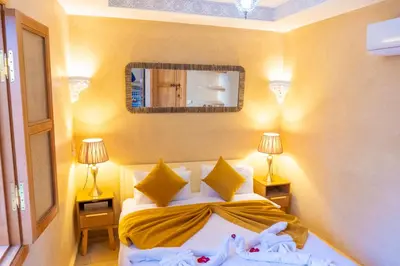 a bedroom with a bed with two lamps and a mirror at Riad Louaya in Marrakech