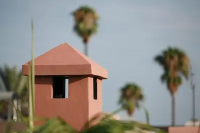 a small red bird house with palm trees in the background at Riad Mariana in Marrakech