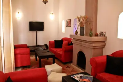 a living room with red furniture and a fireplace at Riad Mariana in Marrakech