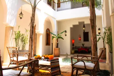 a living room with a table and chairs and a pool at Riad Mariana in Marrakech
