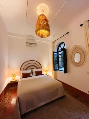 a bedroom with a large bed and a chandelier at Riad Bamaga in Marrakech