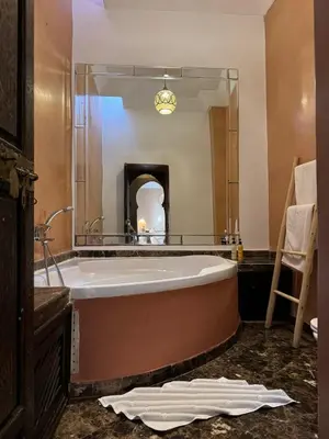 a bath tub in a bathroom with a large mirror at Riad Des Arts in Marrakech