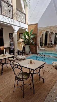 a living room with two tables and a pool at Riad Des Arts in Marrakech