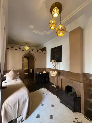 a bedroom with a fireplace and a bed and a table at Riad Des Arts in Marrakech