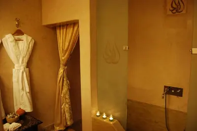 a bathroom with a shower and a robe hanging on a wall at Riad Flam & Spa in Marrakech