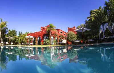 a large pool of water with a red building at Palais El Miria & SPA in Dar Caïd Layadi