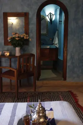a room with a table and a mirror and a table and chair at Riad Azenzer in Marrakech