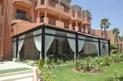 a building with glass doors and flowers in a yard at Palm Plaza Marrakech in Marrakech