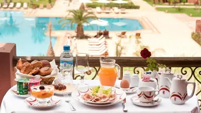 a table with breakfast food and a view of a pool at Palm Plaza Marrakech in Marrakech